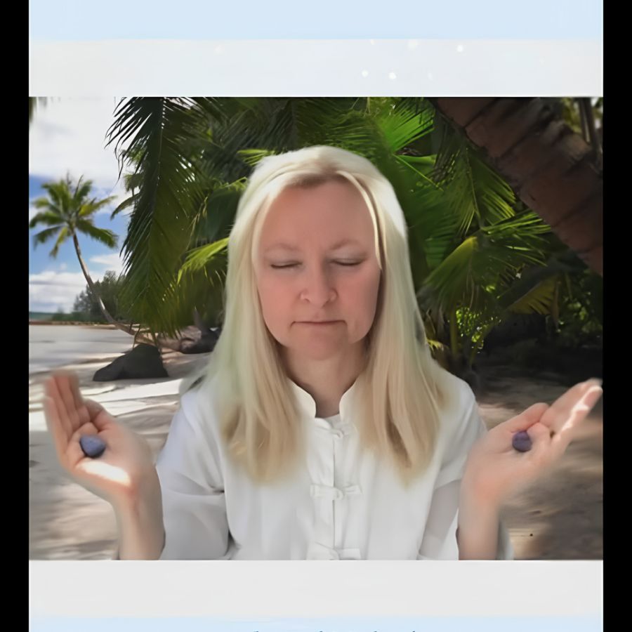 Dorian Lynn, RN, Reiki Master, and energy healer, in meditation pose holding crystals with tropical beach background
